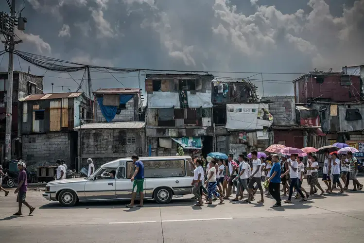 Friends and family of 27-year-old Junmar Abletes follow the hearse carrying his body to the Navotas Catholic Cemetery. Abletes lived on the island of Samar, more than 800 kilometers&nbsp;away, but was killed in Market 3 when he returned for a family visit. Funeral processions like this for young men and women have become common in the past year. Image by James Whitlow Delano. Philippines, 2017.