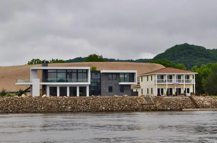 A stockpile of dredged Mississippi River sediment sits behind riverfront homes in Wisconsin. Image by Tristan Baurick / NOLA.com | The Times-Picayune. United States, 2019.