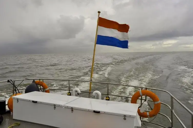 The Dutch flag flutters from the back of a supply boat bound for the Marker Wadden, a series of newly-built islands near Amsterdam. Image by Tristan Baurick / Times-Picayune | The Advocate. The Netherlands, 2020.