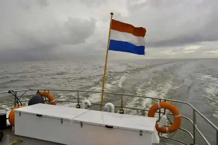 The Dutch flag flutters from the back of a supply boat bound for the Marker Wadden, a series of newly-built islands near Amsterdam.&nbsp;Image by Tristan Baurick / Times-Picayune | The Advocate. The Netherlands, 2020.