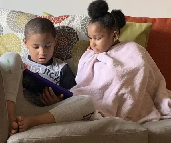 Meegale and Madison Hundley share a tablet to play an educational game during the pandemic. Image by Aisha Sultan /&nbsp;Post-Dispatch. United States, 2020.
