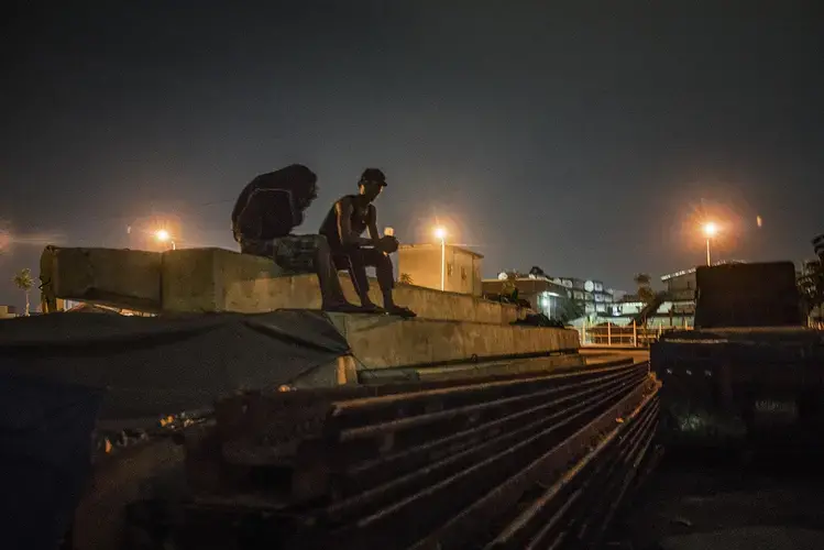 Young men sniff glue hidden in a plastic bottle. Locals say assassins often use this back entrance to sneak into the port in Metro Manila’s Navotas, since the front gate is manned 24 hours a day by armed security guards. Image by James Whitlow Delano. Philippines, 2017.