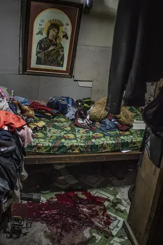 A puddle of blood marks the spot where masked assassins gunned down Francisco Remedillo, a 68-year-old barbecue vendor, and Marlon Dela Cruz, his 36-year-old adopted son, in their little house in Metro Manila’s Quezon City. Dela Cruz was the intended target of the raid. But when Remedillo attempted to intervene, armed with a bat, he, too, was shot dead next to the only bed in their home. Image by James Whitlow Delano. Philippines, 2017.