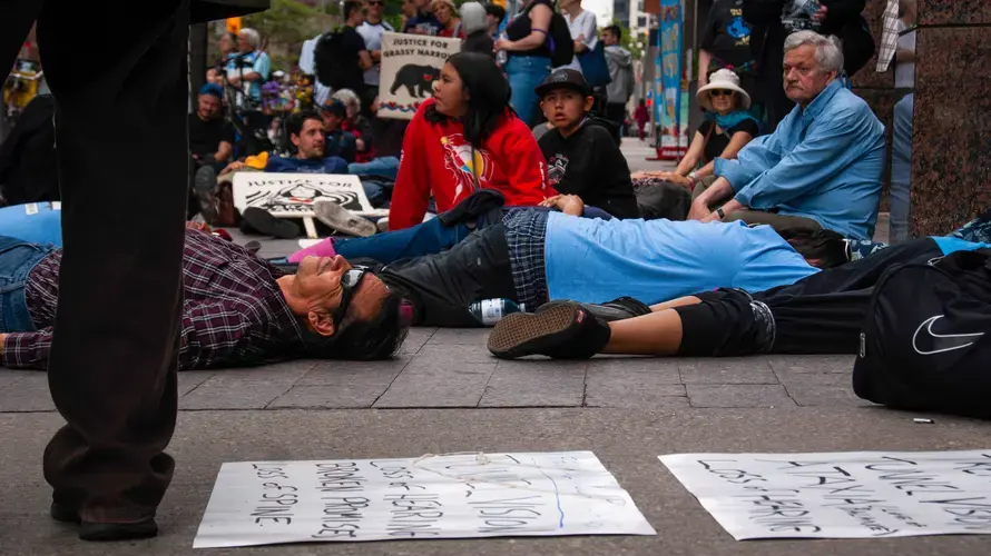 Residents of Grassy Narrows and their supporters lie on the ground in front of the Indigenous Services Canada Office in Toronto. The community organized a 'die-in' in front of the office to remind the Canadian government of their suffering.&nbsp;Image by Shelby Gilson. Canada, 2019.