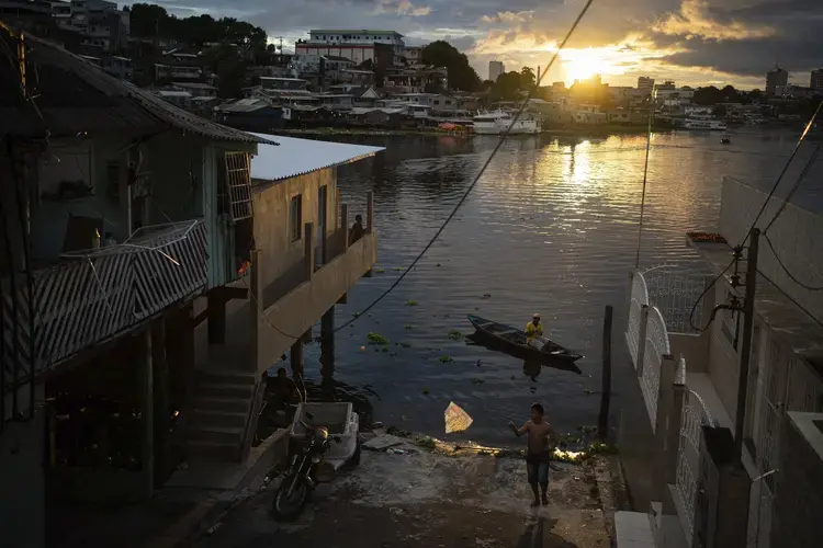 A boy flies a kite by the riverside in Manaus, Brazil, Sunday, May 24, 2020. Per capita, Manaus is Brazil's major city hardest hit by COVID-19. Image by Felipe Dana / AP Photo. Brazil, 2020.