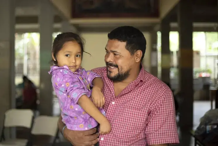 Walter Sanchez Reyes holds his daughter Maria Dolores Sanchez at a migrant shelter in southern Mexico. Sanchez was shot by gang members while driving a bus in Tegucigalpa, Honduras. The family plans to request asylum in the United States. Image by Miguel Gutierrez Jr. Mexico, 2019.