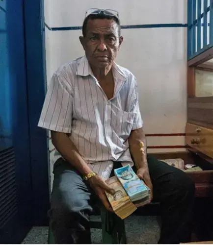 The owner of a local gold pawn shop in Tumeremo, Bolivar state, shows a stack of Venezuelan money, worth only a few dollars due to the nation’s rapidly escalating inflation. Image by Bram Ebus. Venezuela, 2017.<br />
