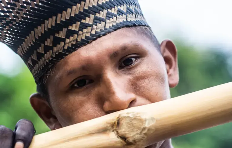 Playing on a bamboo flute during ritual preparations. Photo by Matheus Manfredini. Brazil, 2019.