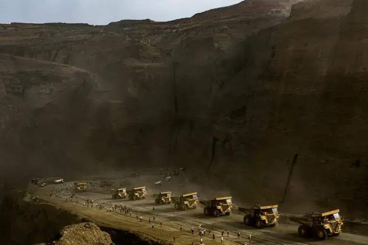 Freelance jade miners rush past a line of company trucks during a two-hour break at a government-licensed jade mining site, when they are allowed to search through discarded tailings but must turn over larger stones to the mining company, in Hpakant on May 17, 2019. Image by Hkun Lat. Myanmar, 2019.
