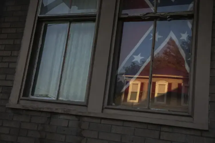 A confederate flag hangs in the window of a home of a young Black woman in Shawnee Ohio. Image by Wong Maye-E/AP Photo. United States, 2020.