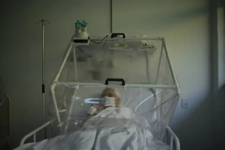 An elderly COVID-19 patient is treated inside a non-invasive ventilation system named the Vanessa Capsule at a municipal field hospital Gilberto Novaes in Manaus, Brazil, Monday, May 18, 2020. Image by Felipe Dana / AP Photo. Brazil, 2020.