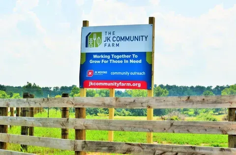 A sign for The JK Community Farm with the phrase, "Working Together to Grow for Those in Need".