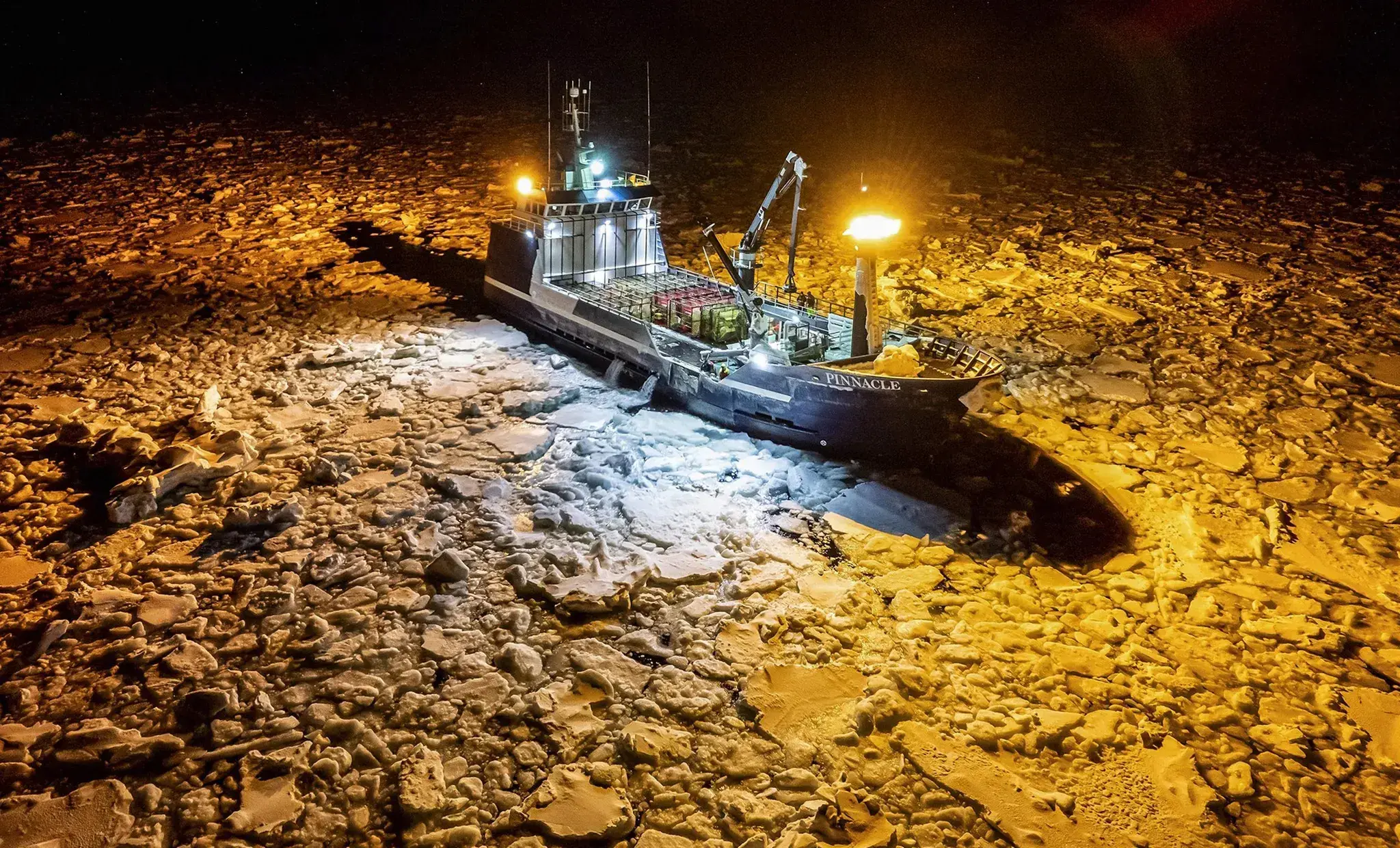 an ice crab fishing boat at night surrounded by ice