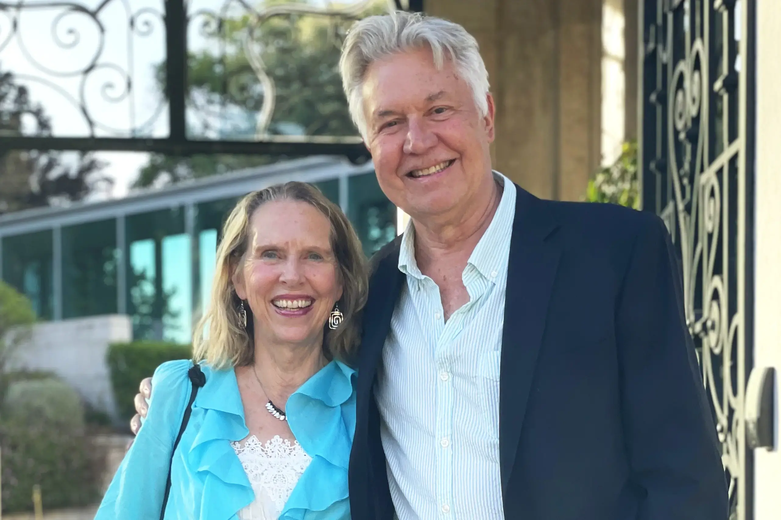 Jon, wearing a suit jacket, and Kem Sawyer, wearing a bright blue dress, pose for a photo in Lisbon