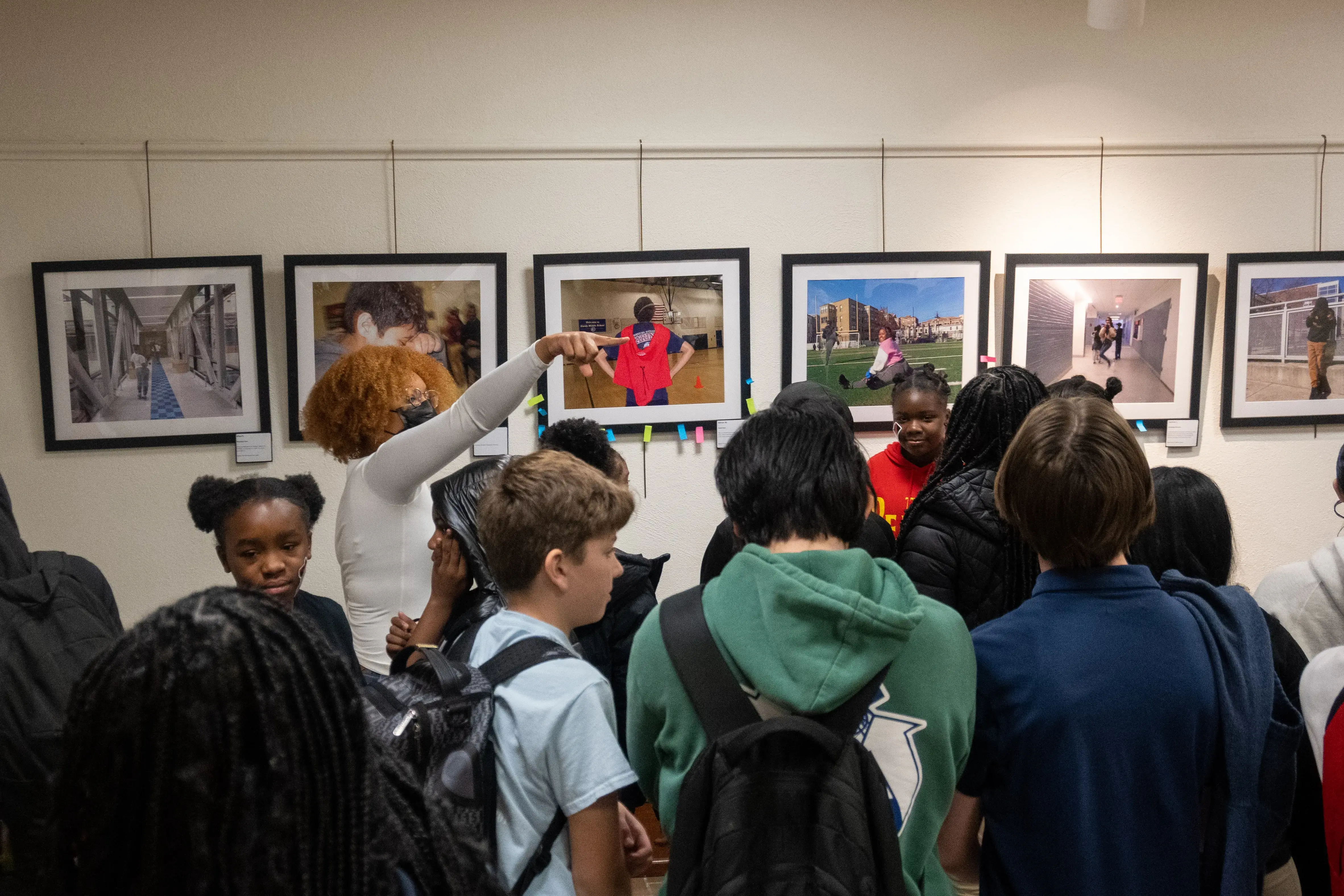A facilitator from the Pulitzer center guides a conversation with students in the Everyday DC gallery of framed photographs