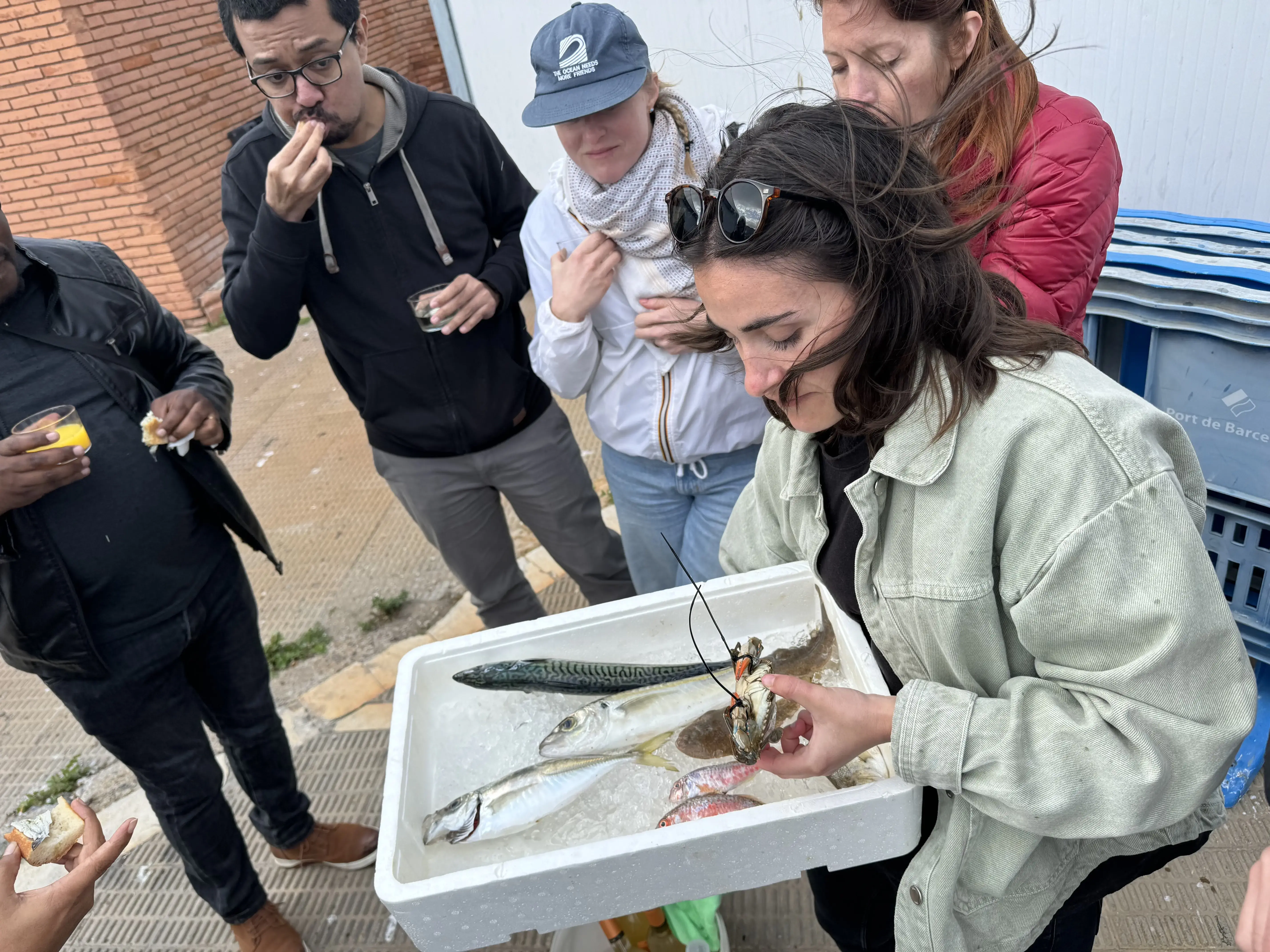 A woman shows a box with fish in it to the group