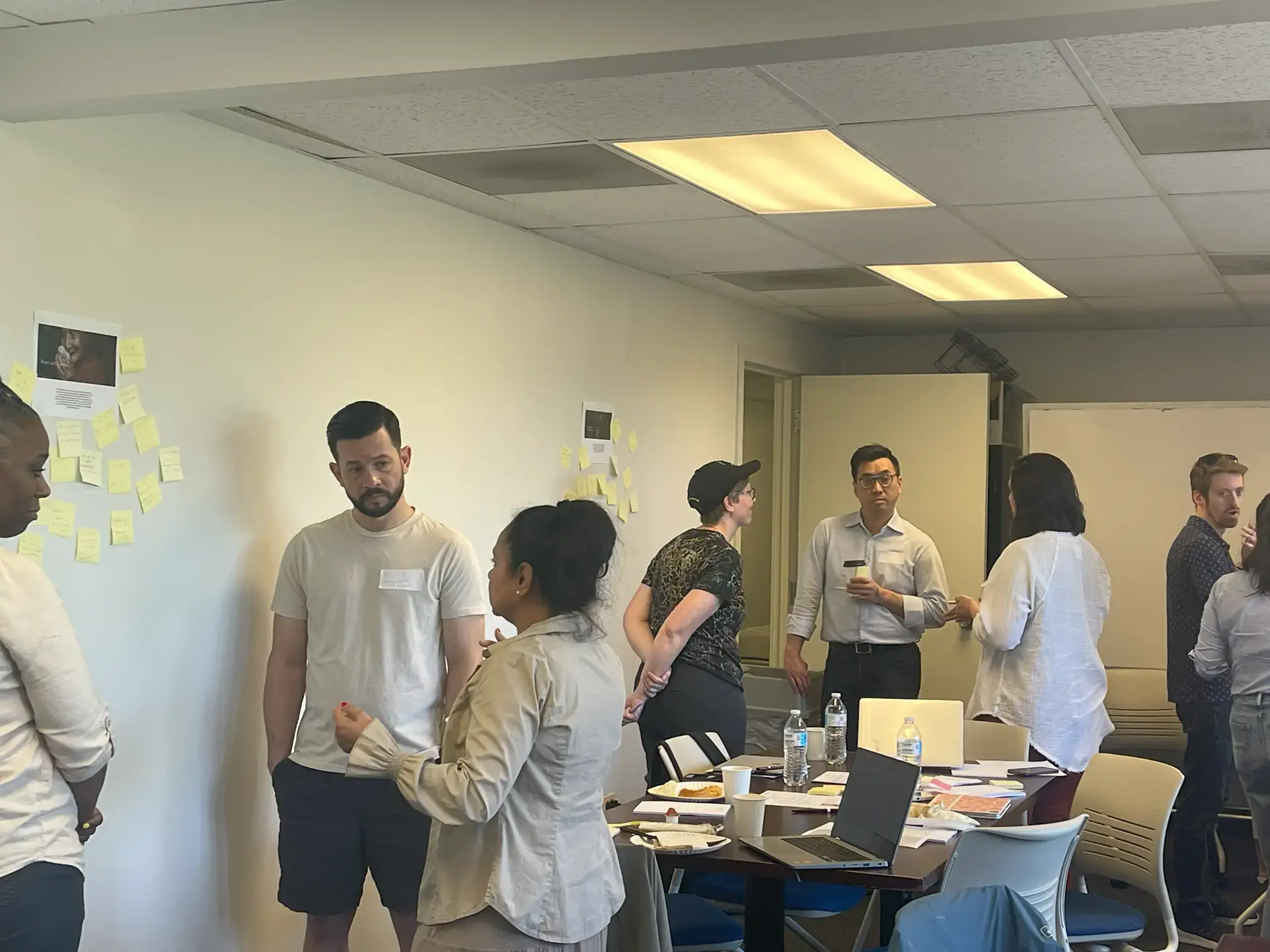 Teachers gather in a conference room. There are three groups of 3 people, all chatting about something.