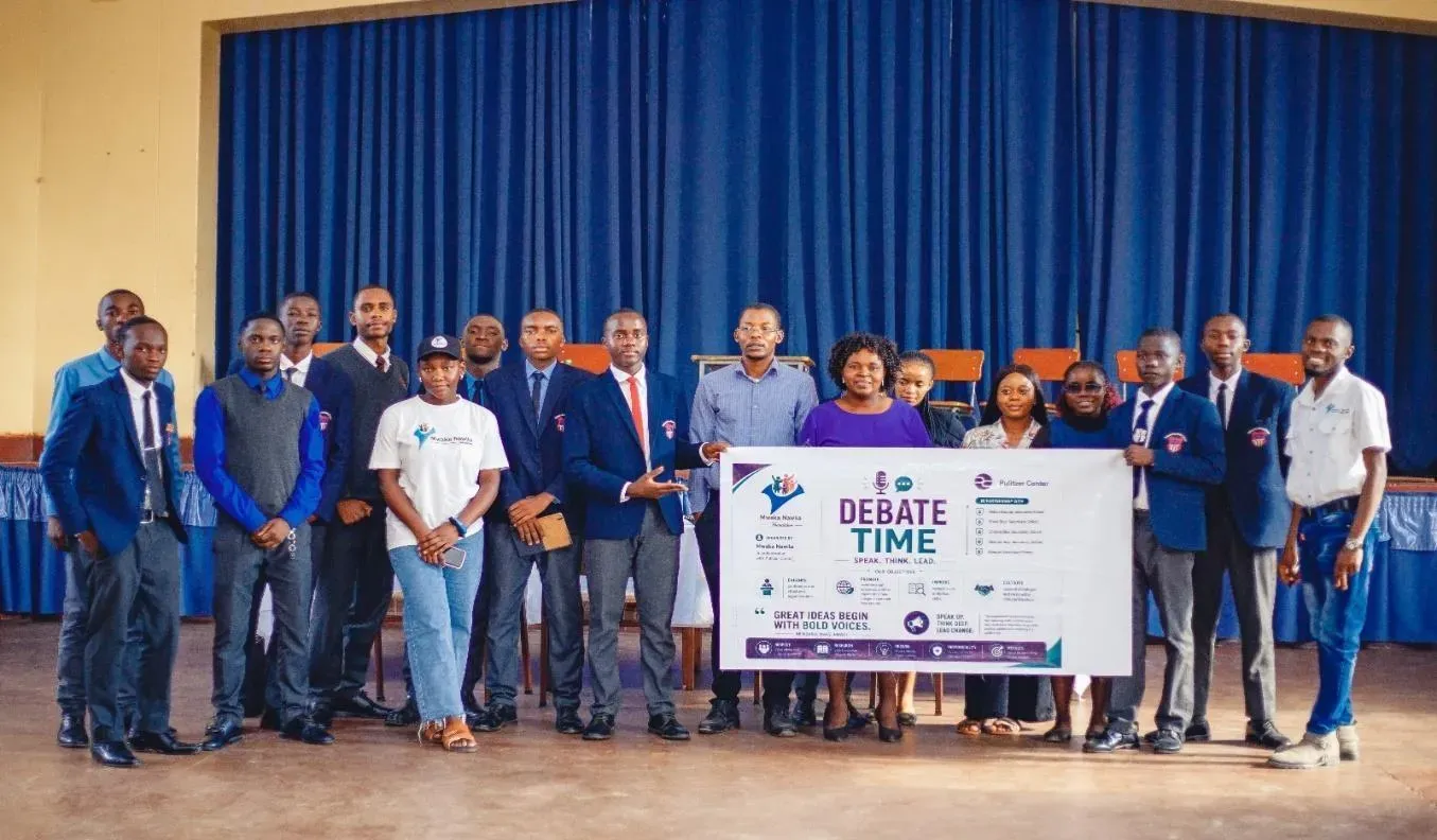 A group photo holding a banner from the event called 'debate time' with the logos of the sponsors.