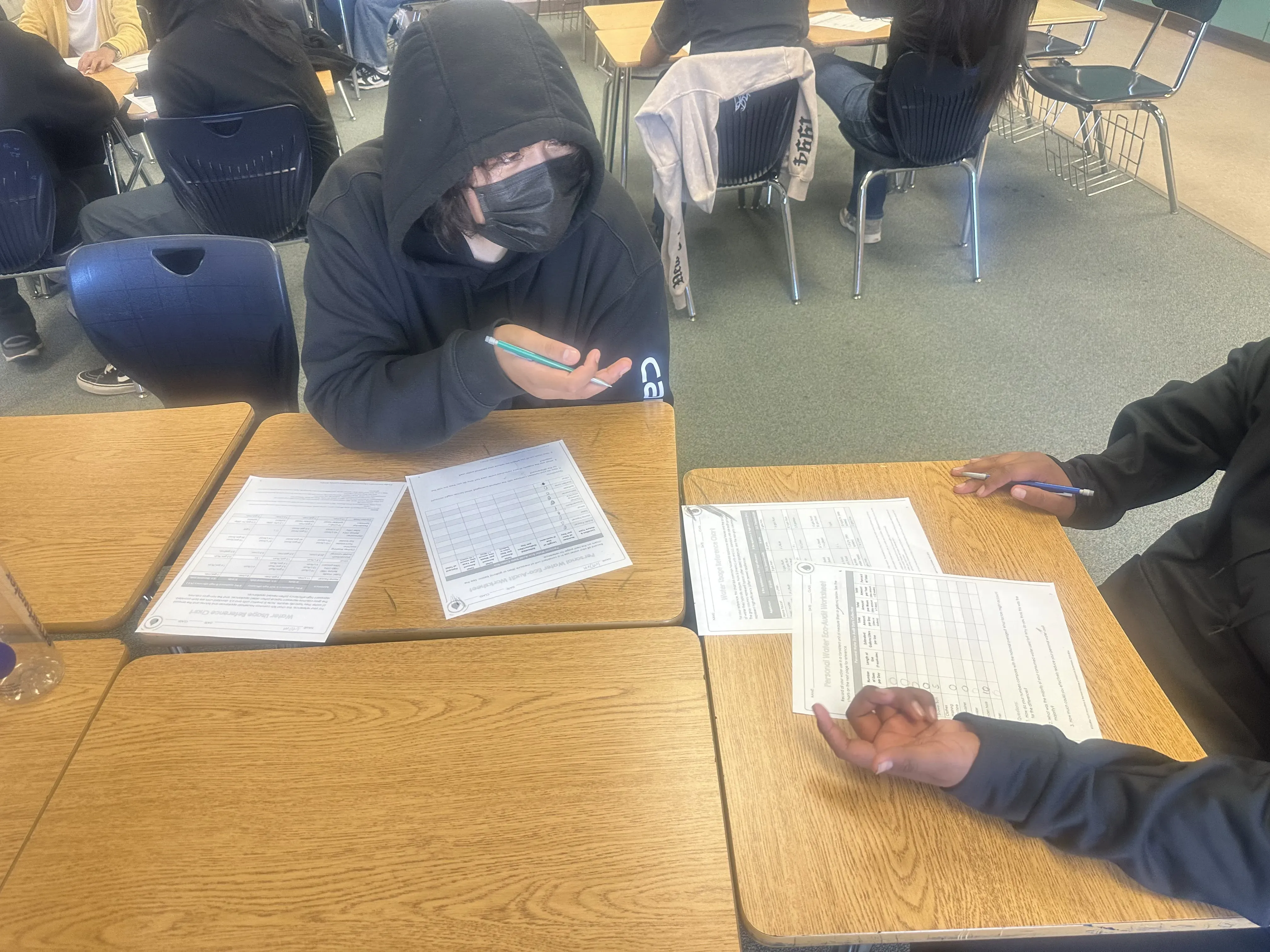 two seated students complete a worksheet at their desks