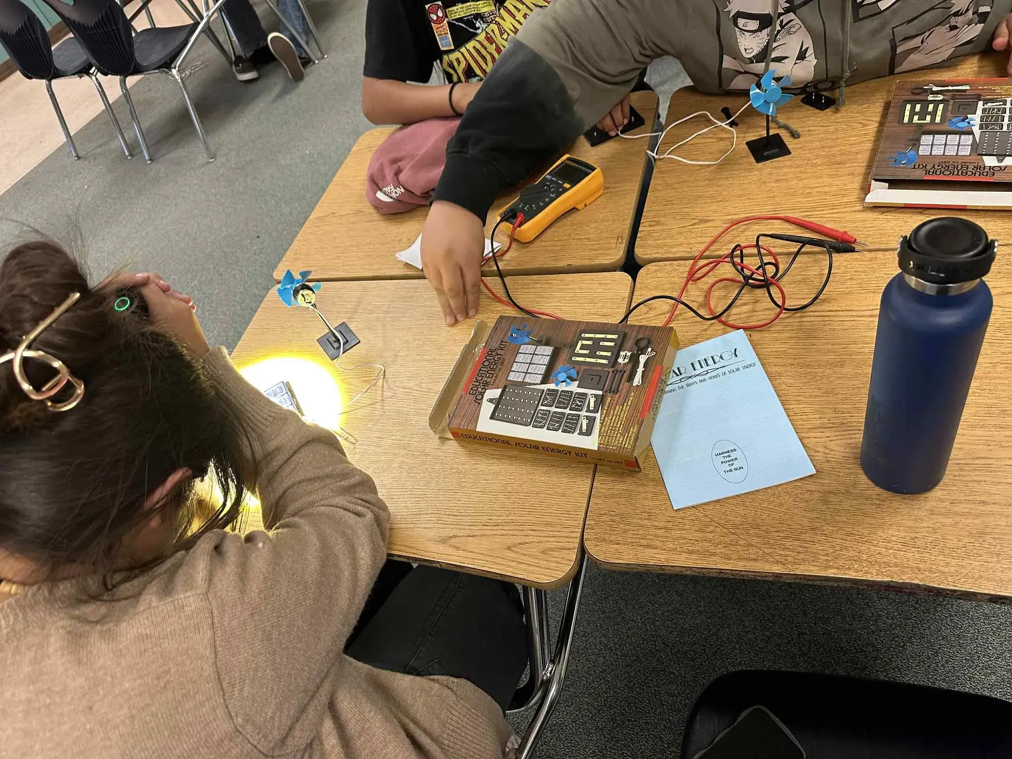 two seated students complete activity with solar panels on desk