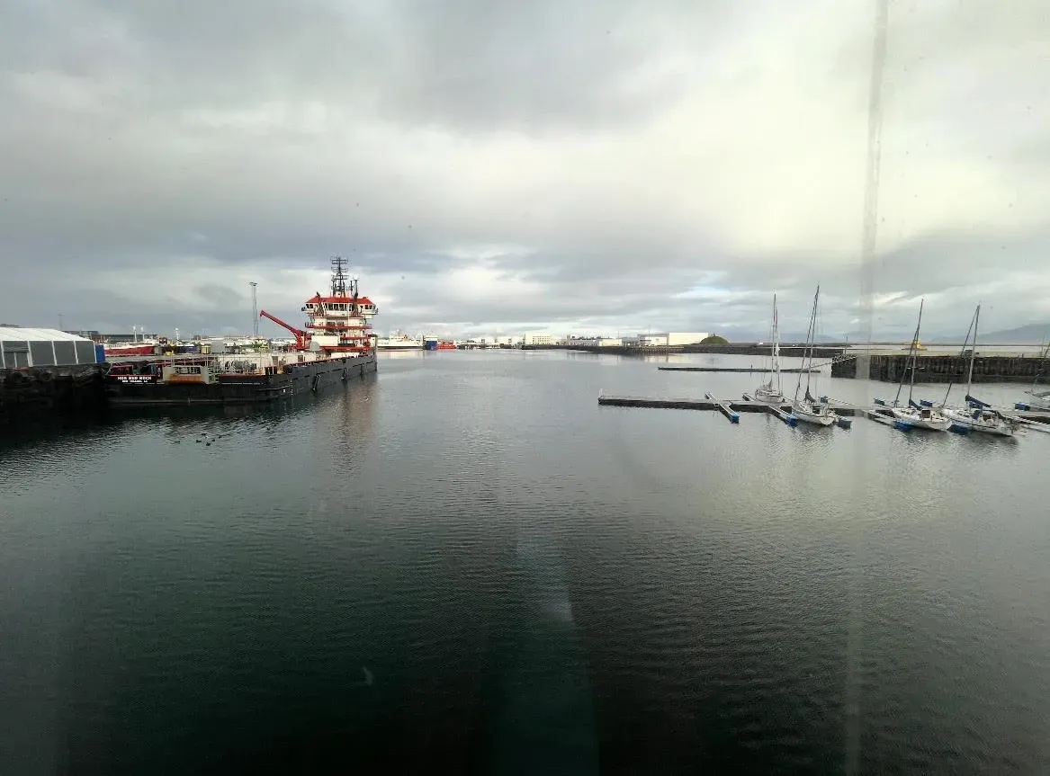 A harbor holds one large, docked ship and several smaller boats.