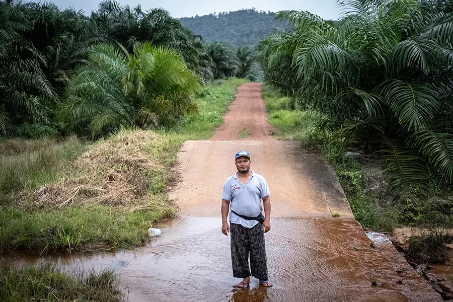 a man stands on a stretch of road where a creek runs perpendicular to and over the pavement.