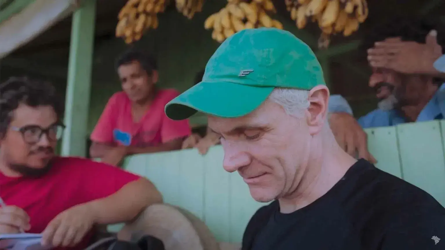 A man in a green hat looks down at the ground.