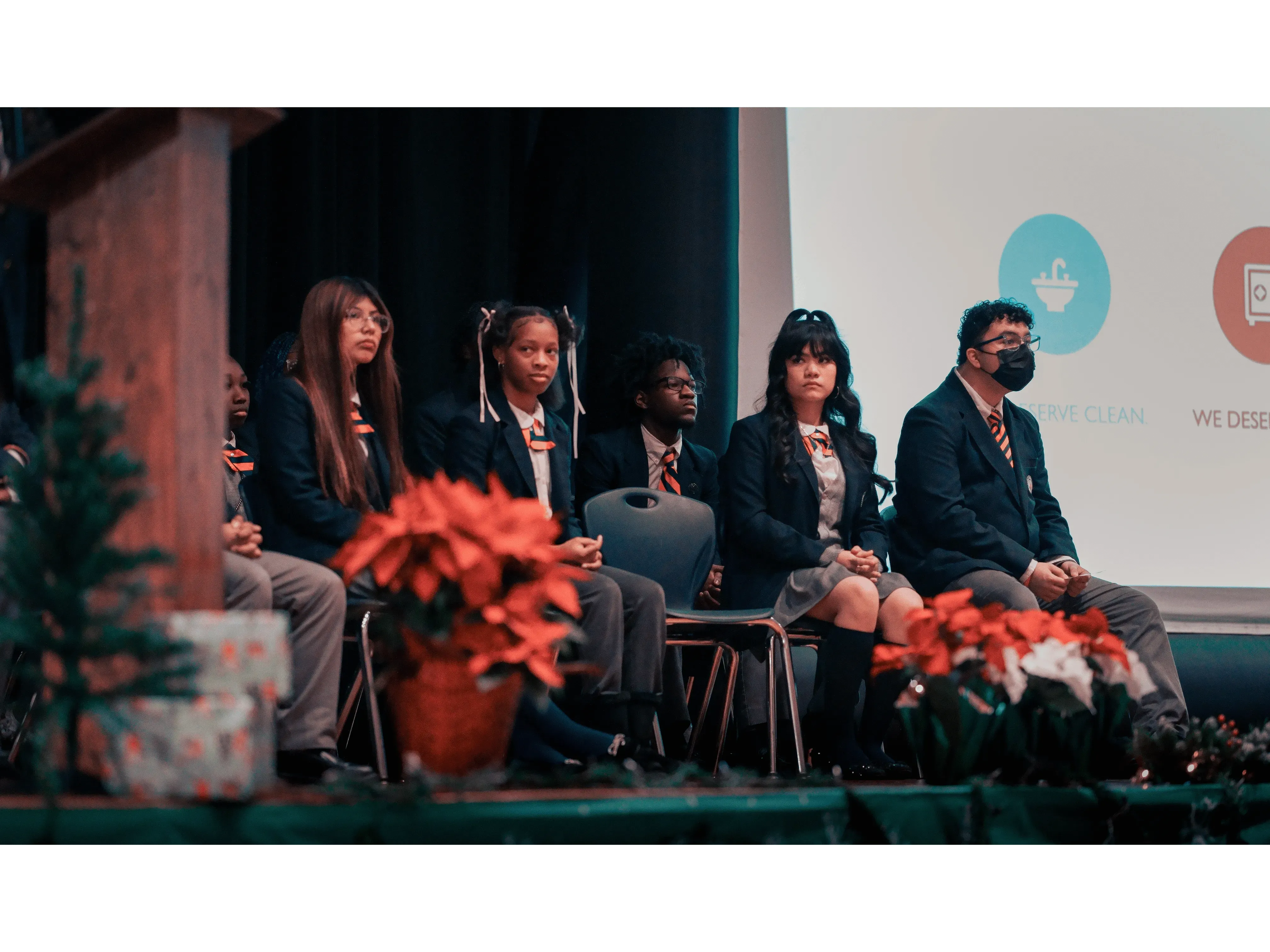 student presenters seated onstage during the school symposium 