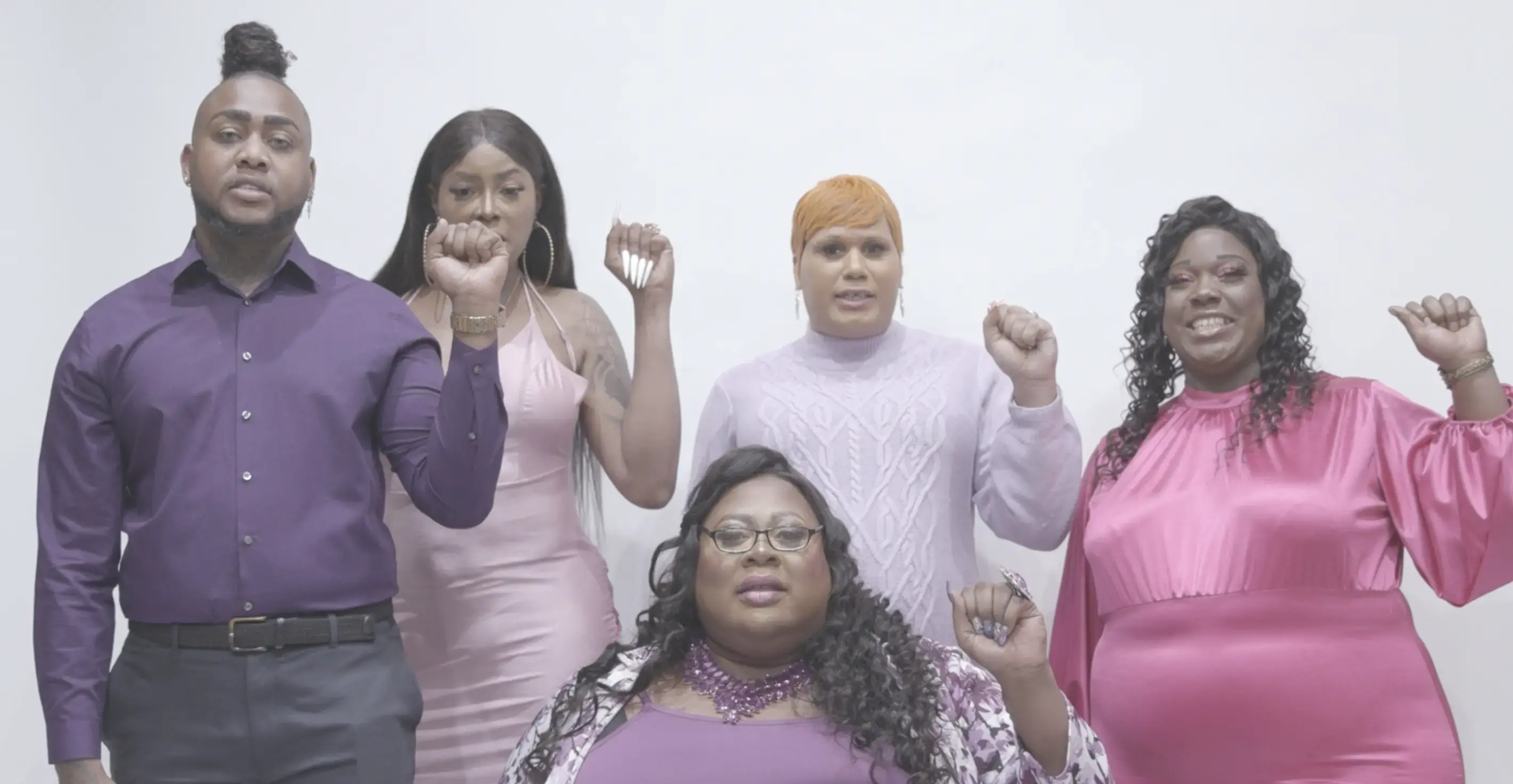 Five people stand facing the camera while raising their fists.