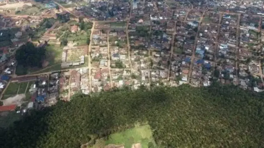 aerial image of forrested area adjacent to a town with dirt roads