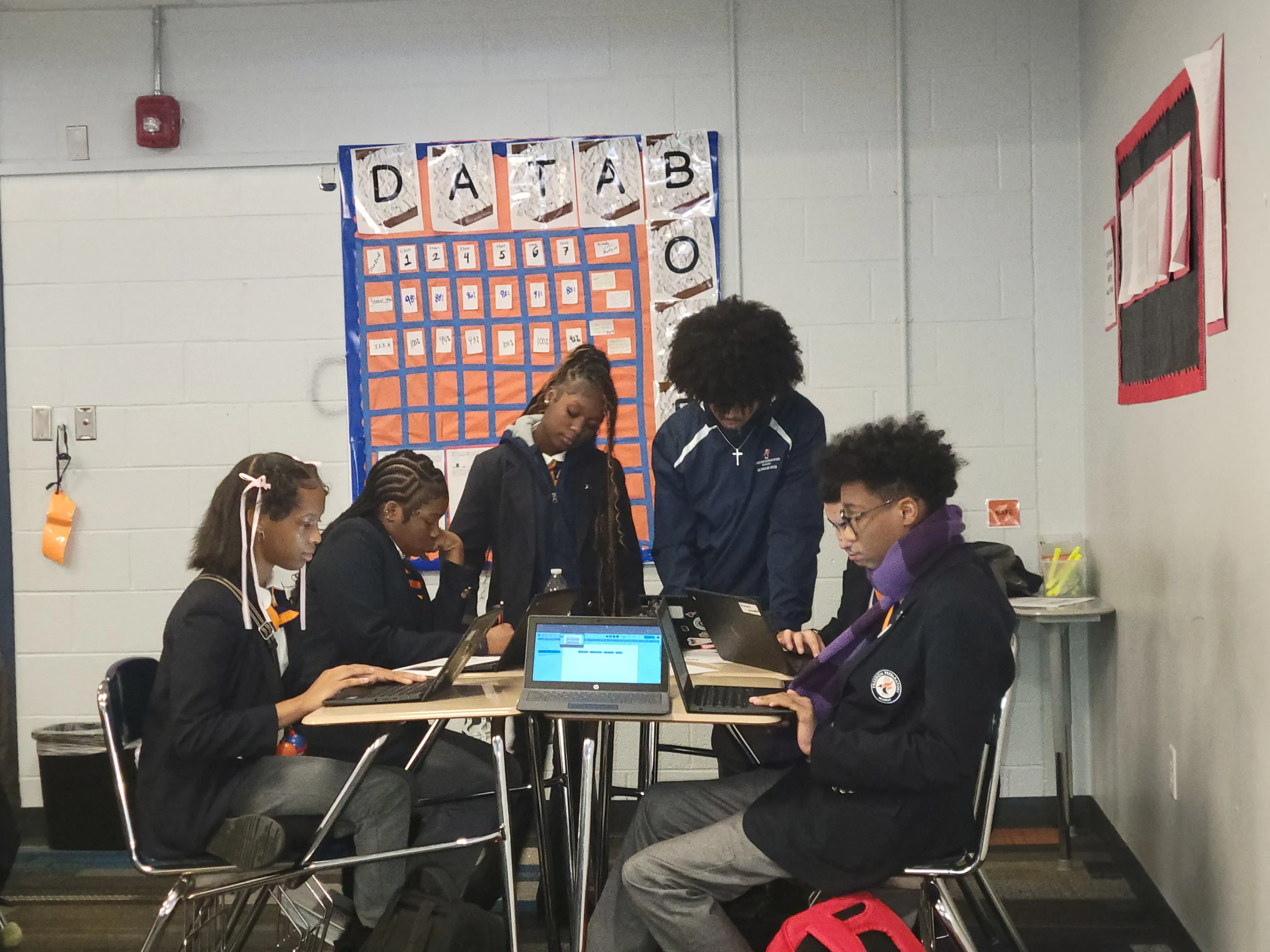 A small group of students sitting together at desks working on laptops