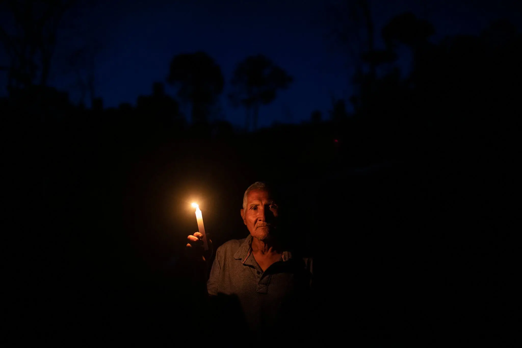 Lourenço Durães at his home on the banks holding a candle