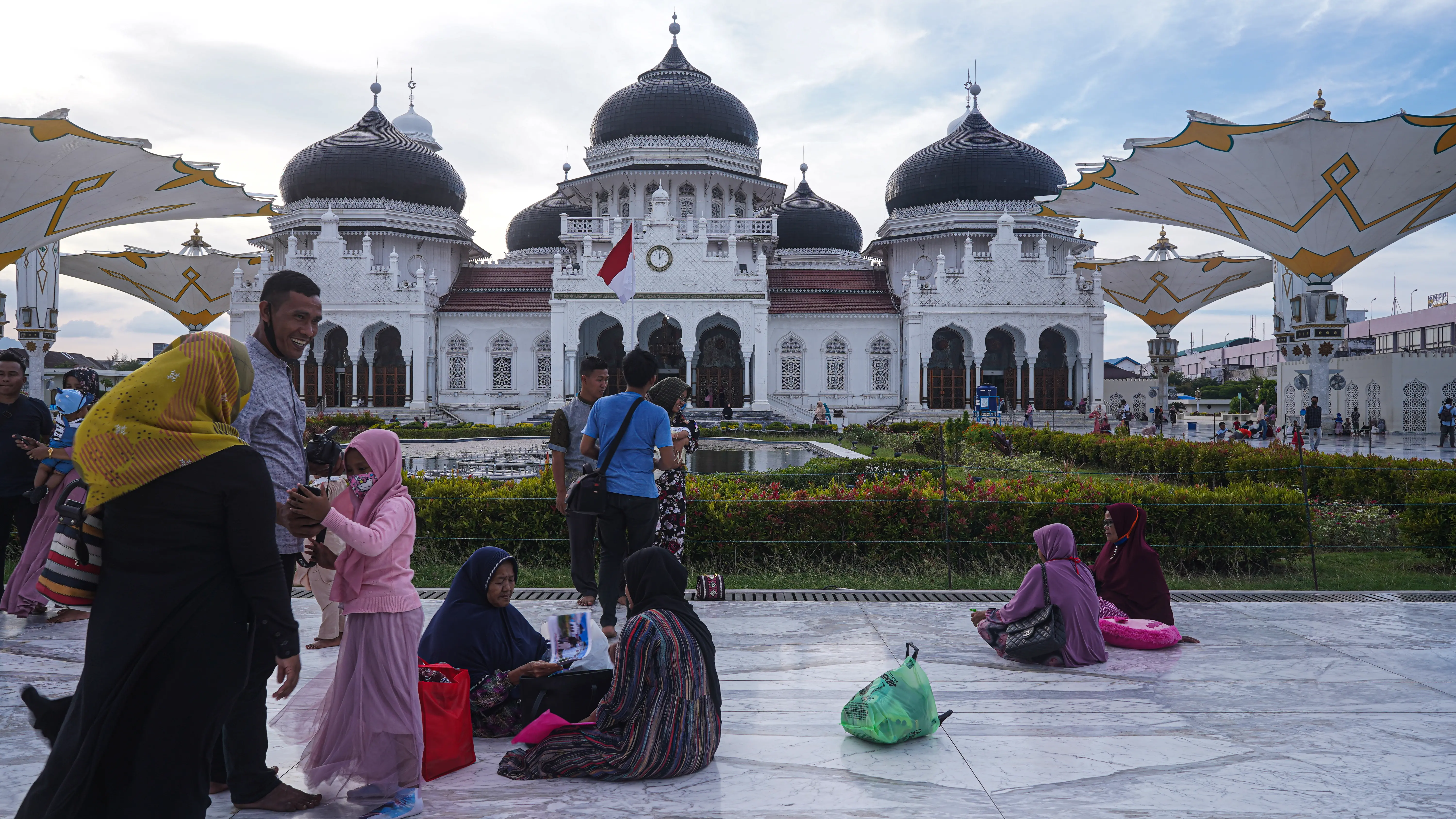 People sit and walk outside a mosque.