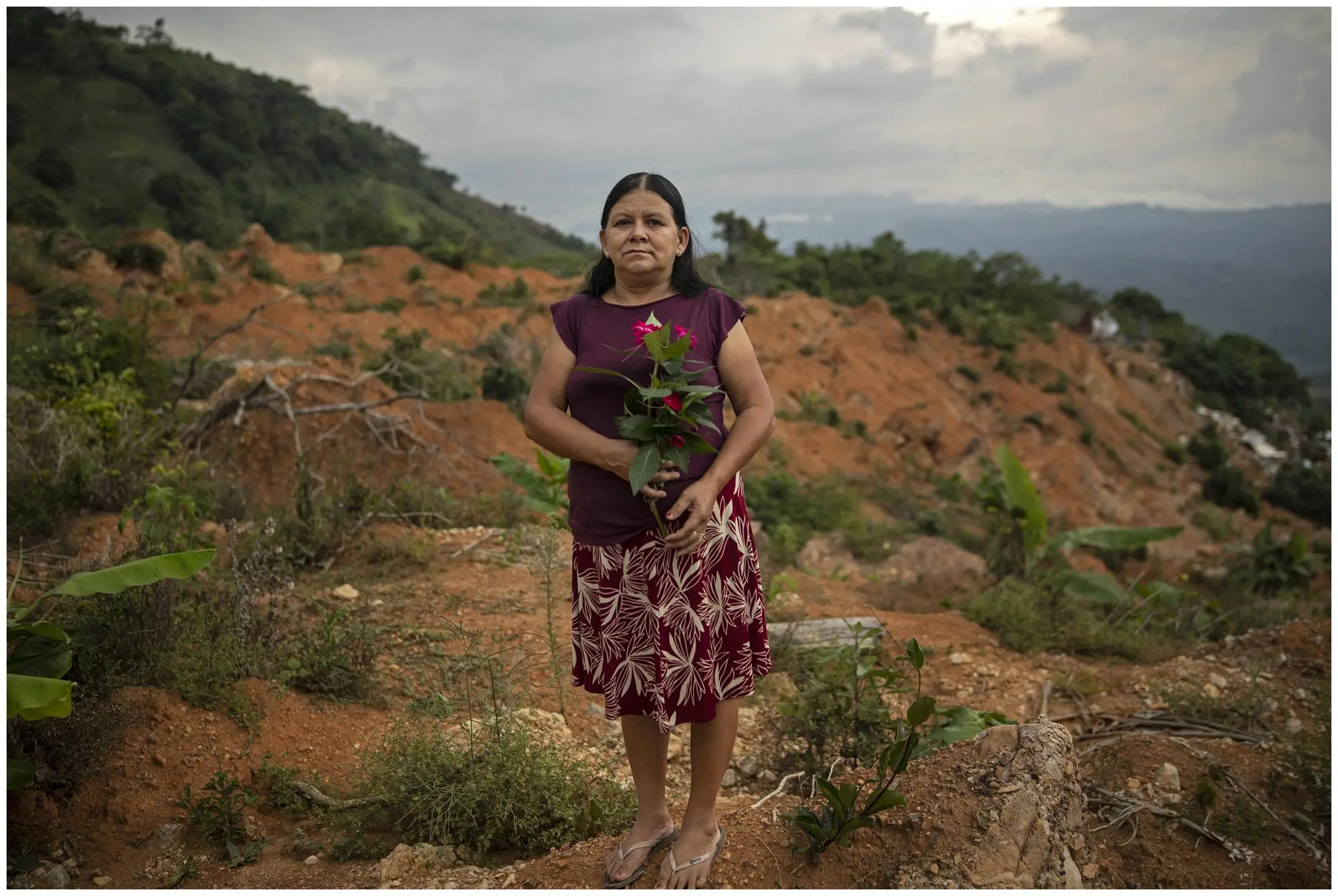 A woman stands for a portrait where her home used to be