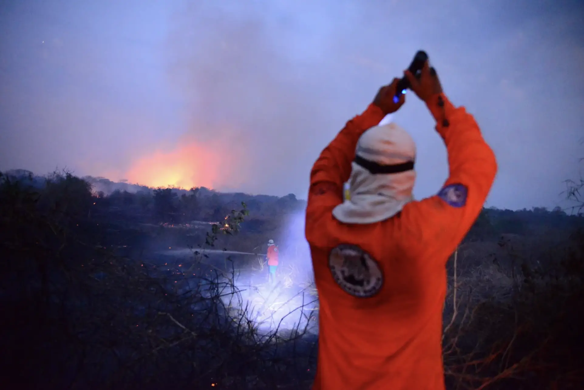 A firefighter shines a flashlight on a another firefighter 