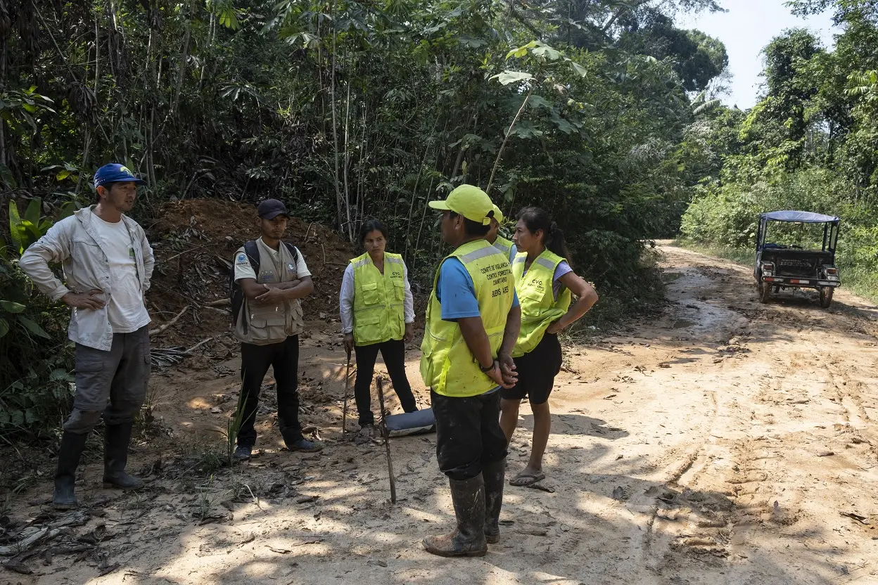 Six people are standing and talking to each other. All are wearing hiking clothes. 