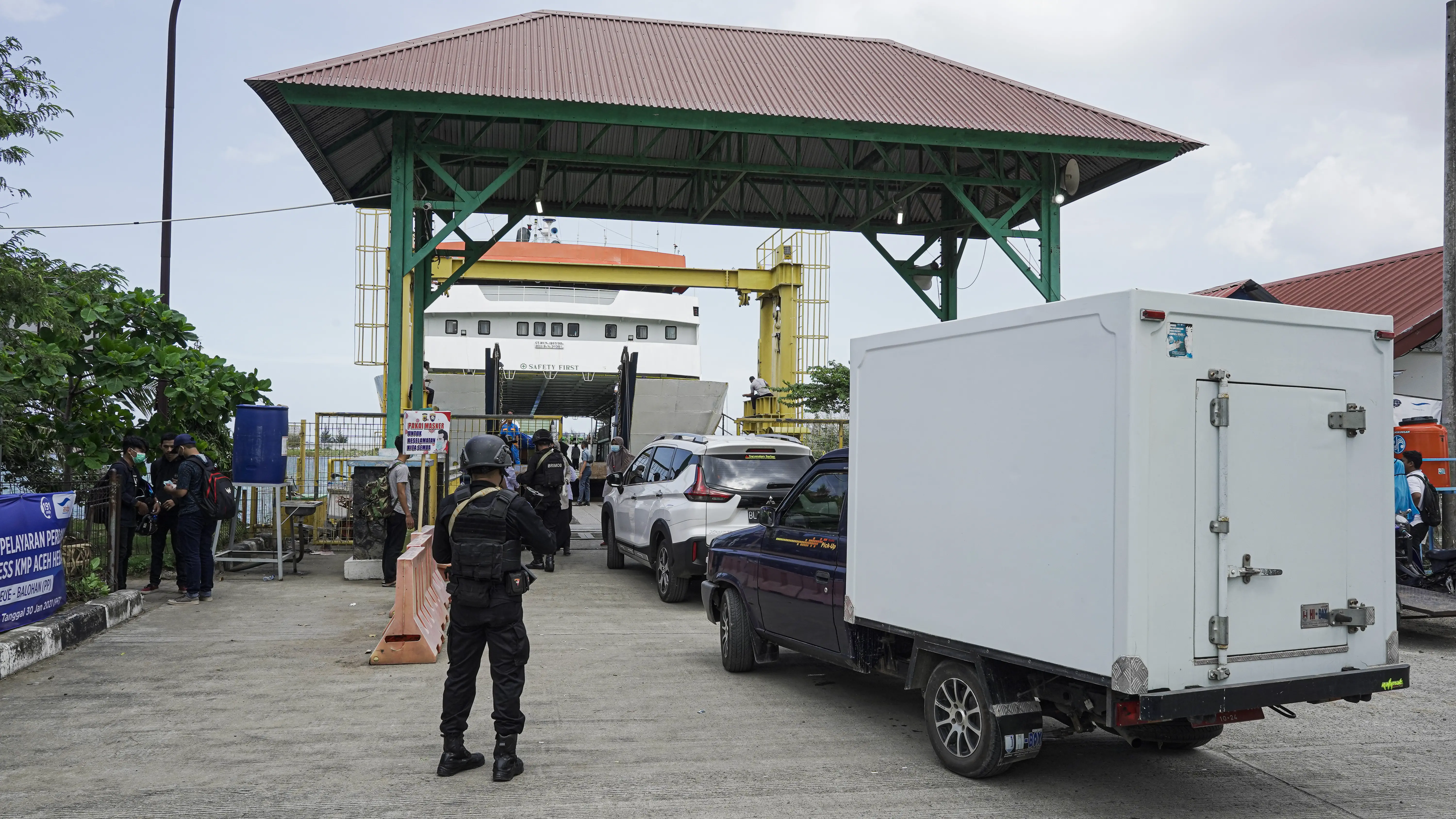 A truck carrying vaccines lines up behind other vehicles to board a ferry at a port.