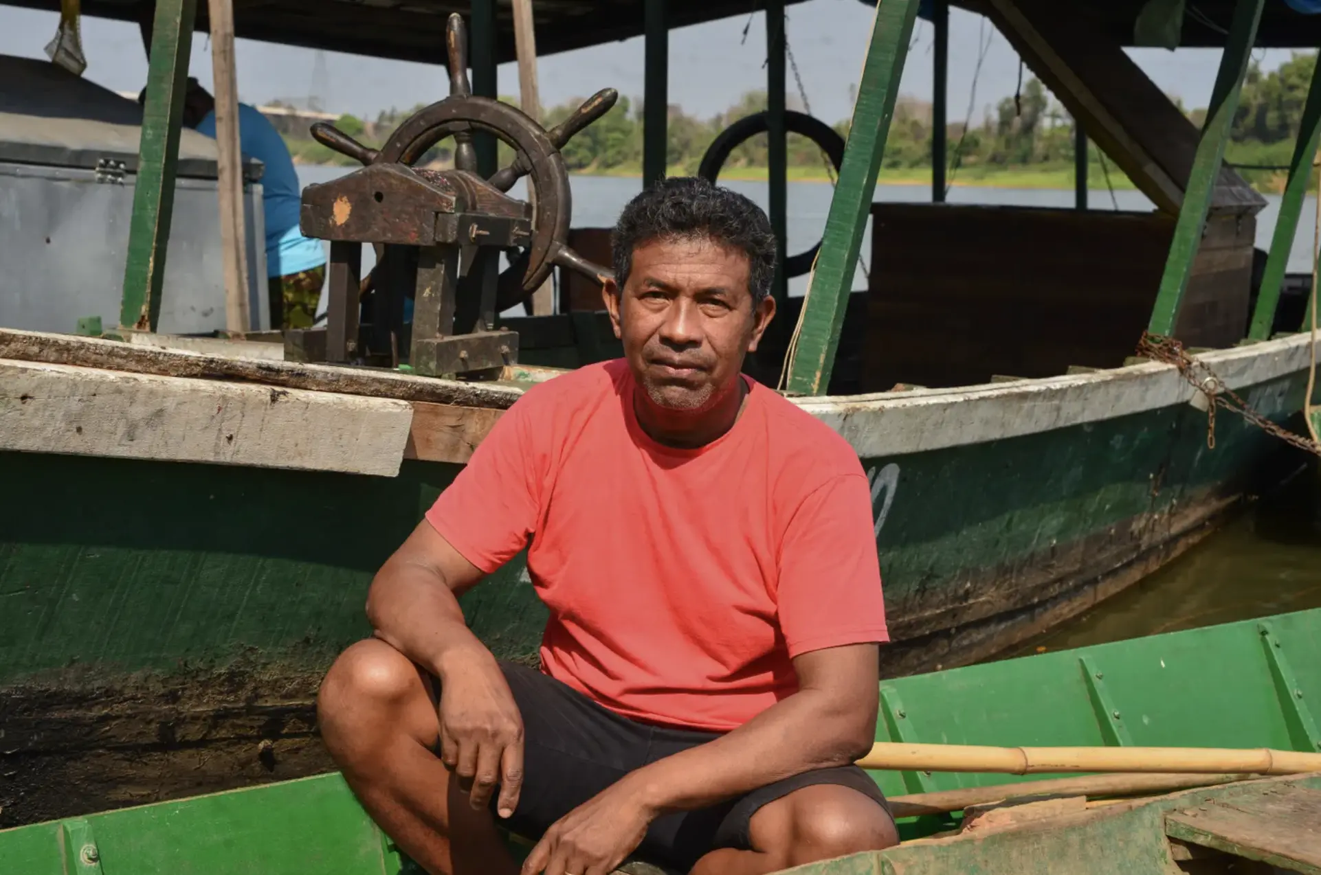 A man sits on a boat in a dock area