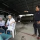 Manager Daiu Saingam talks with employees waiting for farmers to deliver milk at the Pakchong Dairy Cooperative in Pak Chong, Thailand. Image by Mark Hoffman. Thailand, 2019. 