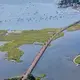 The Northeast Corridor Line, a 735-kilometer stretch of rail line, often follows the shoreline, such as here, near Groton, Connecticut. Soon the route could be beset by episodes of submersion that would erode the trackbed and disable signaling equipment, disrupting travel for the approximately 12 million passengers who rely on it each year. A recent study of a 16-kilometer segment owned by Amtrak near Wilmington, Delaware, proposed a $78-million package of flood barriers that could be erected during storms. Image by Alex MacLean. United States, 2019.