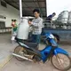 A farmer drops off a single can of milk at Prateep Farms in Pak Chong, Thailand. Owner Prateep Kaewnun milks about 400 cows and purchases milk from small farms in the area. The quality of milk he purchases must be equal to that of his modern farm. Image by Mark Hoffman. Thailand, 2019. 