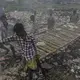 With little in the way of collection services, trash is often found smoldering in the streets, adding to the ambient waves of particulate matter. Image by Larry C. Price. Bangladesh, 2018.