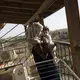 Noor Al Talaa, 22, stands on the balcony at dusk with baby Rahaf, almost 6 months, at an apartment in Sidros. Image by Lynsey Addario. Greece, 2017.
