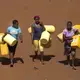 Women carry water jugs outside a facility where residents can buy clean drinking water in the Kawangware slum. Image by Mark Hoffman. Kenya, 2017. 