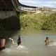Migrants swim and wash clothes in the Rio Grande under the Gateway International Bridge in Matamoros. Image by Miguel Gutierrez Jr. Mexico, 2019.