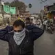 The open burning of trash  adds to the daily cloud. Here, a man ties a scarf over his face after encountering a smoldering pile of trash. Image by Larry C. Price. India, 2018.